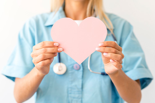 front-view-female-doctor-with-stethoscope-holding-paper-heart